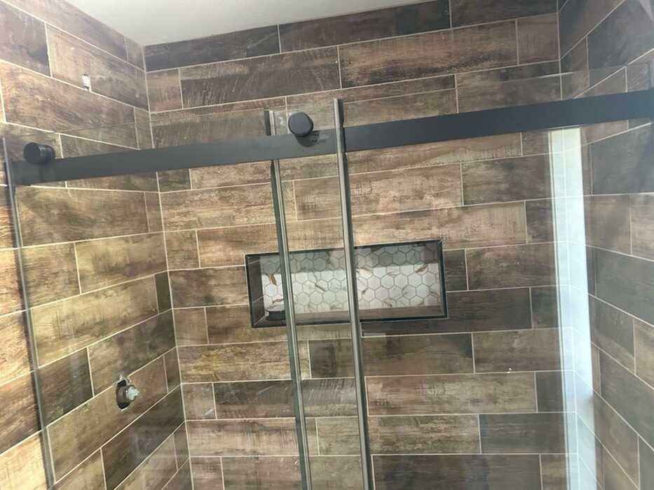 Custom glass shower door with wood tile by Glass And Window Solutions